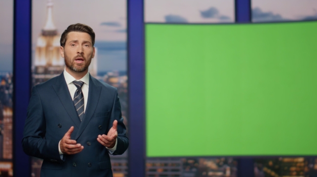 Elegant host reporting breaking news standing near green screen close up. Confident calm newscaster talking daily events gesturing closeup. Bearded presenter hosting newscast at multimedia tv channel.